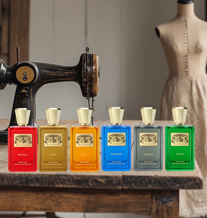 All six Extrait de Parfums lined up on a workbench in front of a tailor's sewing machine and mannequin