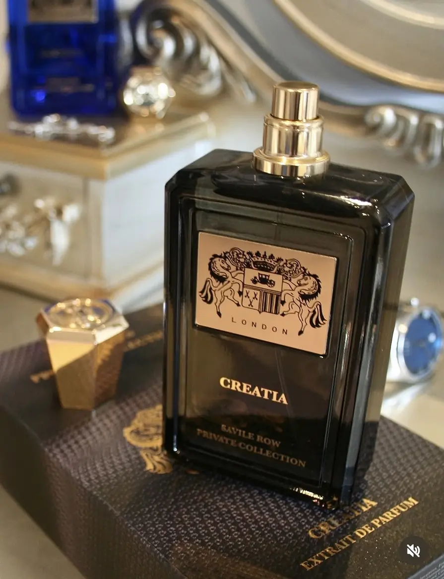 Creatia Extrait de Parfum photographed with gold jewellery and a watch case